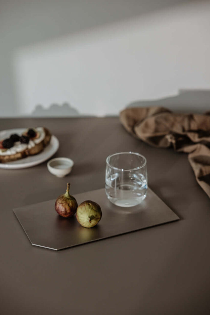 Dekotablett mit frischen Früchten und einem Glas Wasser auf einem Tisch, perfekte Dekoration für jedes Zuhause.