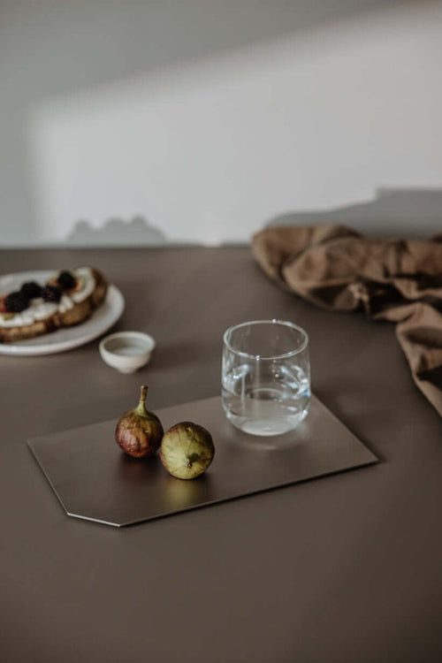 Dekotablett mit frischen Früchten und einem Glas Wasser auf einem Tisch, perfekte Dekoration für jedes Zuhause.