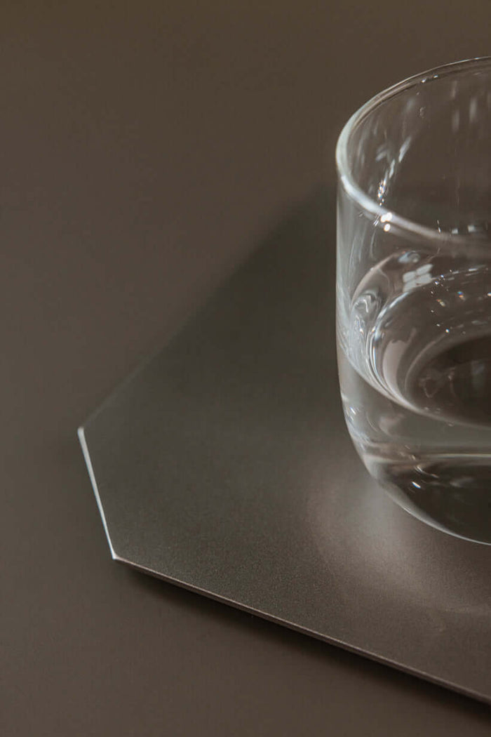 Dekotablett mit Glas Wasser, modernes Design aus gestrahltem Edelstahl, flaches Accessoire für Zuhause.