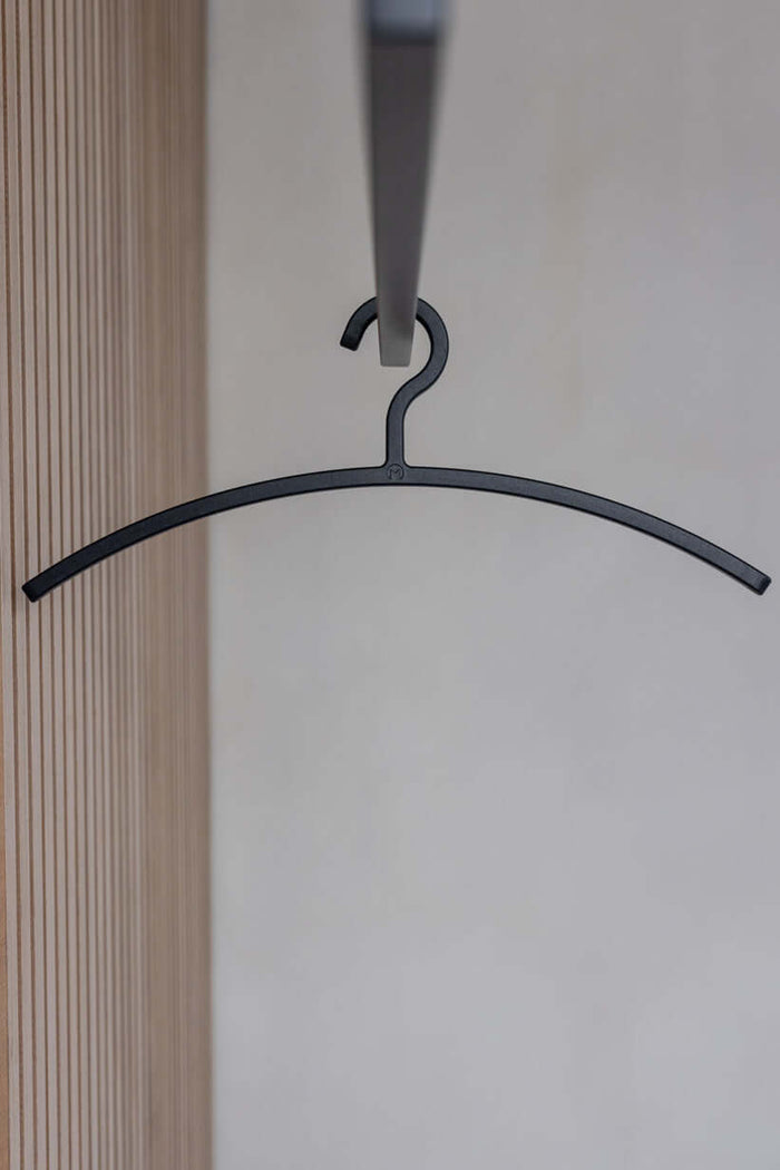 Schwarzer Kleiderbügel FAY hängt an einer Garderobe, minimalistisches Design für moderne Ästhetik.