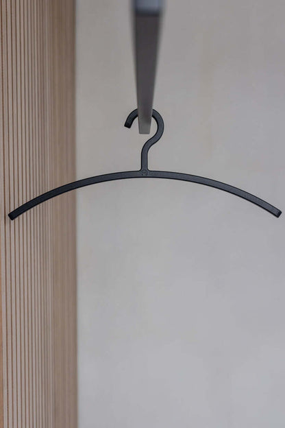 Schwarzer Kleiderbügel FAY hängt an einer Garderobe, minimalistisches Design für moderne Ästhetik.