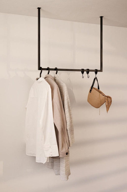 Kleiderstange RUBI mit weißen Hemden und einer Tasche an der Wand, elegantes minimalistisches Design für jedes Ankleidezimmer.
