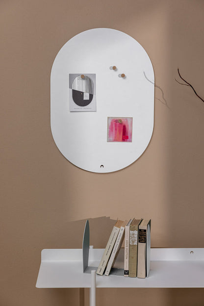 Elegante Magnettafel TAVO an der Wand mit Notizen und Büchern auf dem Tisch darunter.