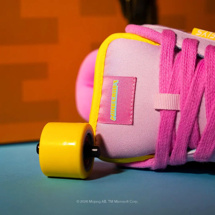 A close-up of a pink skate shoe with bright pink laces, a yellow wheel, and a pink heel counter, resting on a blue surface with an orange background.