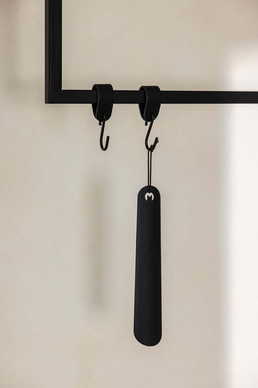 Schuhlöffel TILO in Schwarz an Haken, minimalistisches Design aus hochwertigem Metall.